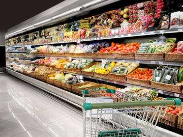 A vegetable grocery aisle with an empty trolley in the bottom right