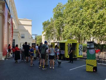 A yellow horsebox surrounded by people