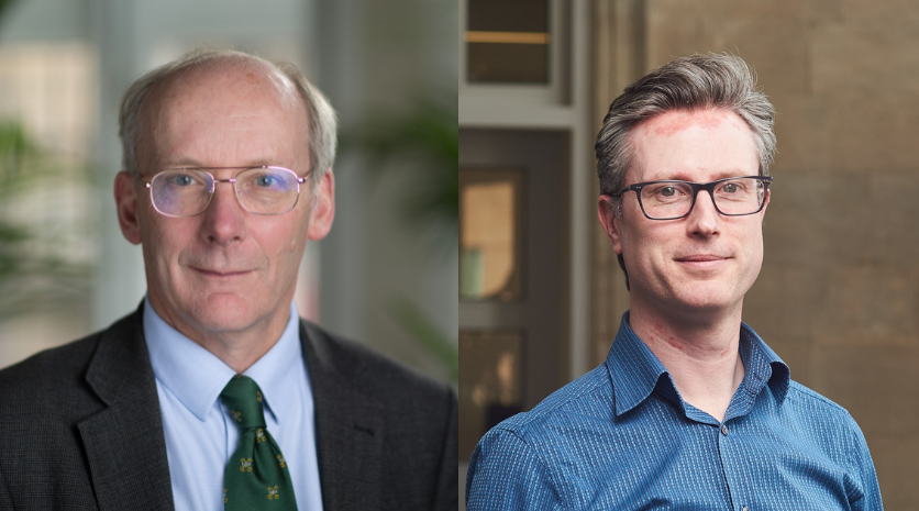Two white men stand in profile next to each other. On the left, the man is wearing glasses with a tie and blazer. On the right, the man has grey hair, glasses, and a blue shirt.