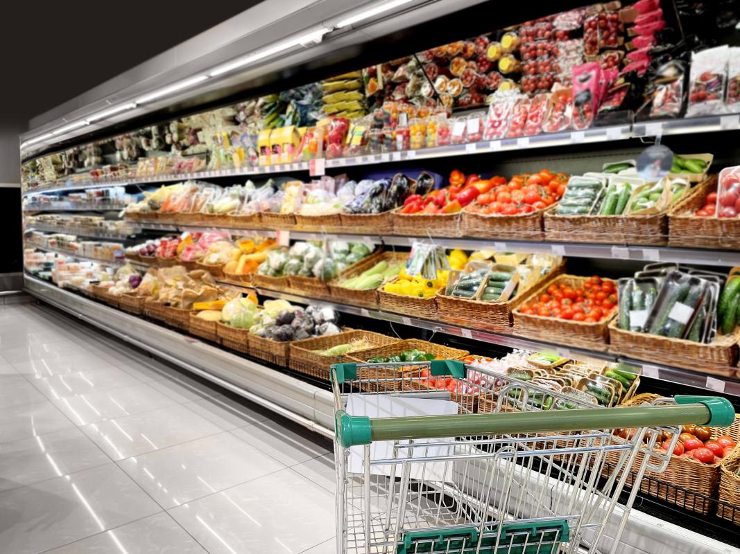 A vegetable grocery aisle with an empty trolley in the bottom right