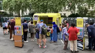 People standing around in front of a yellow horsebox that says Meat Your Persona