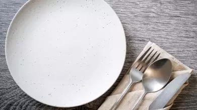 An empty plate with a knife and fork on the side