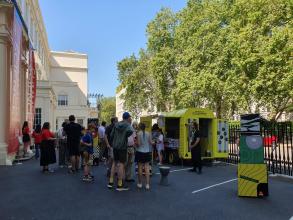 A yellow horsebox surrounded by people
